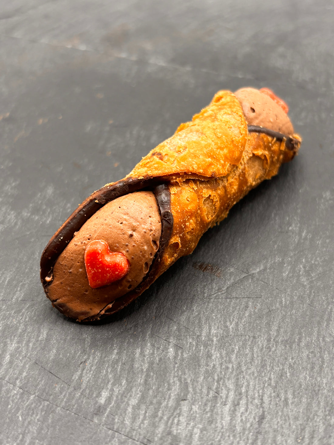 Cannoli L'Amore - Een heerlijk traditioneel Siciliaans gebakje gevuld met romige chocolade, versierd met een rood chocolade hartje.
